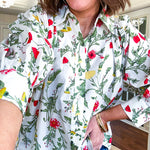 Cream 3/4 sleeve button down top with collar and pleating at the yoke with red, yellow and green florals throughout.
