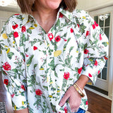 Cream 3/4 sleeve button down top with collar and pleating at the yoke with red, yellow and green florals throughout.