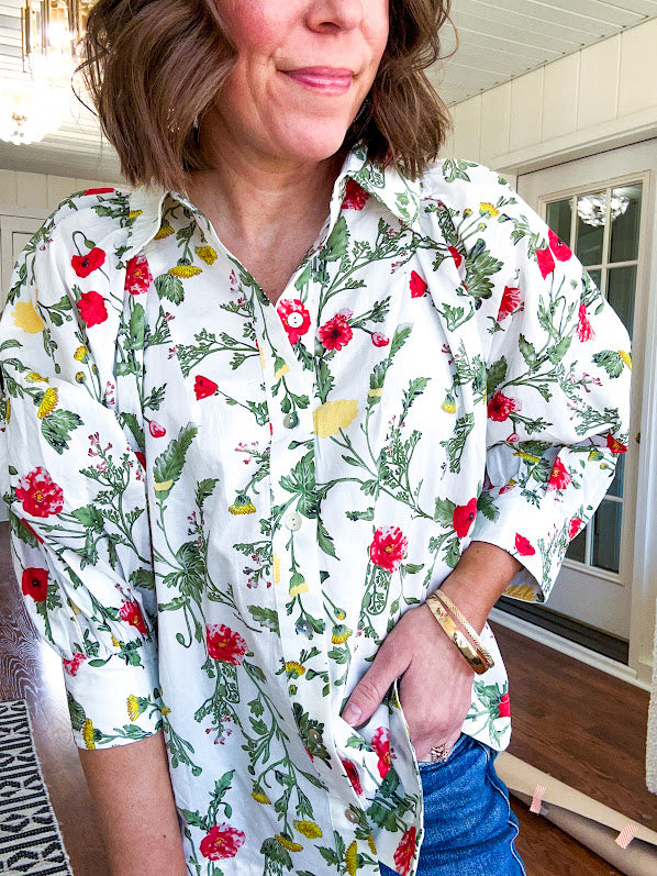 Cream 3/4 sleeve button down top with collar and pleating at the yoke with red, yellow and green florals throughout.