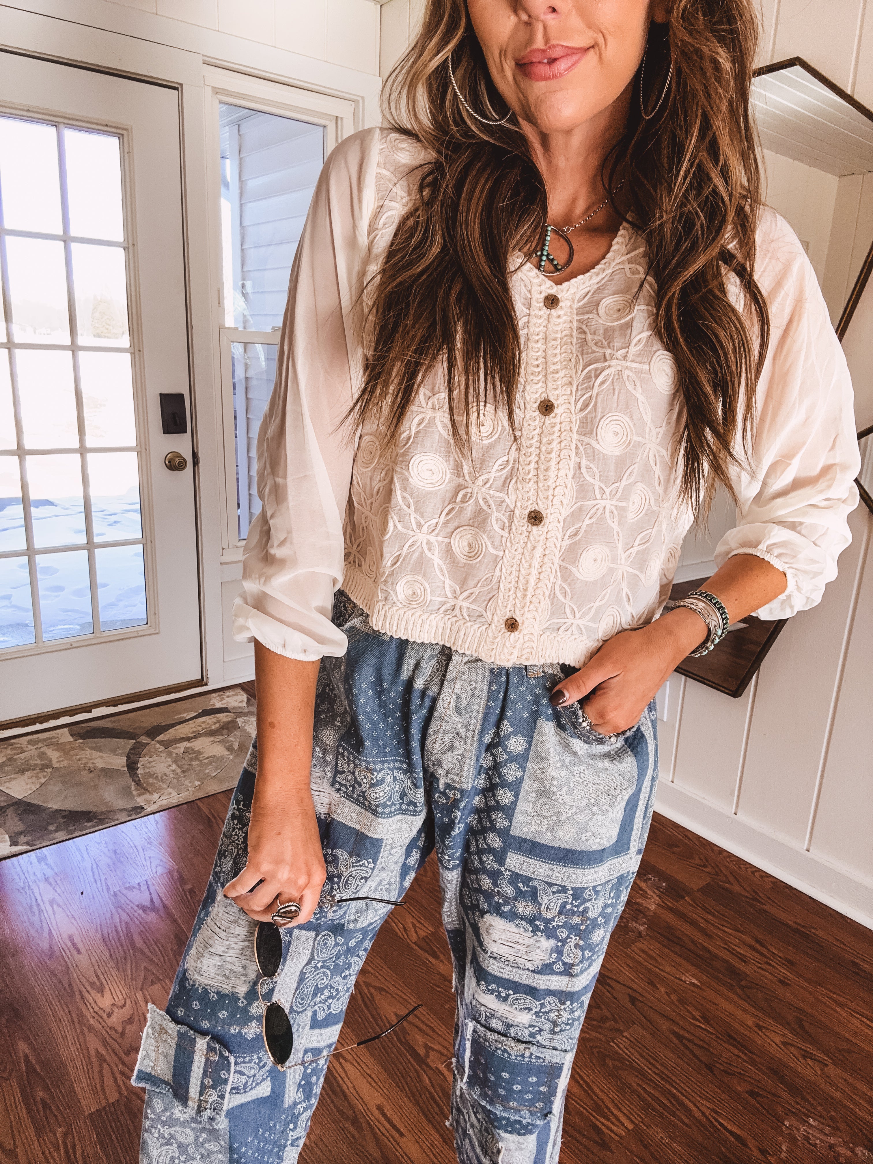 Short sheer beige button down long sleeved top with whimsical embroidery throughout and elastic cuffs.