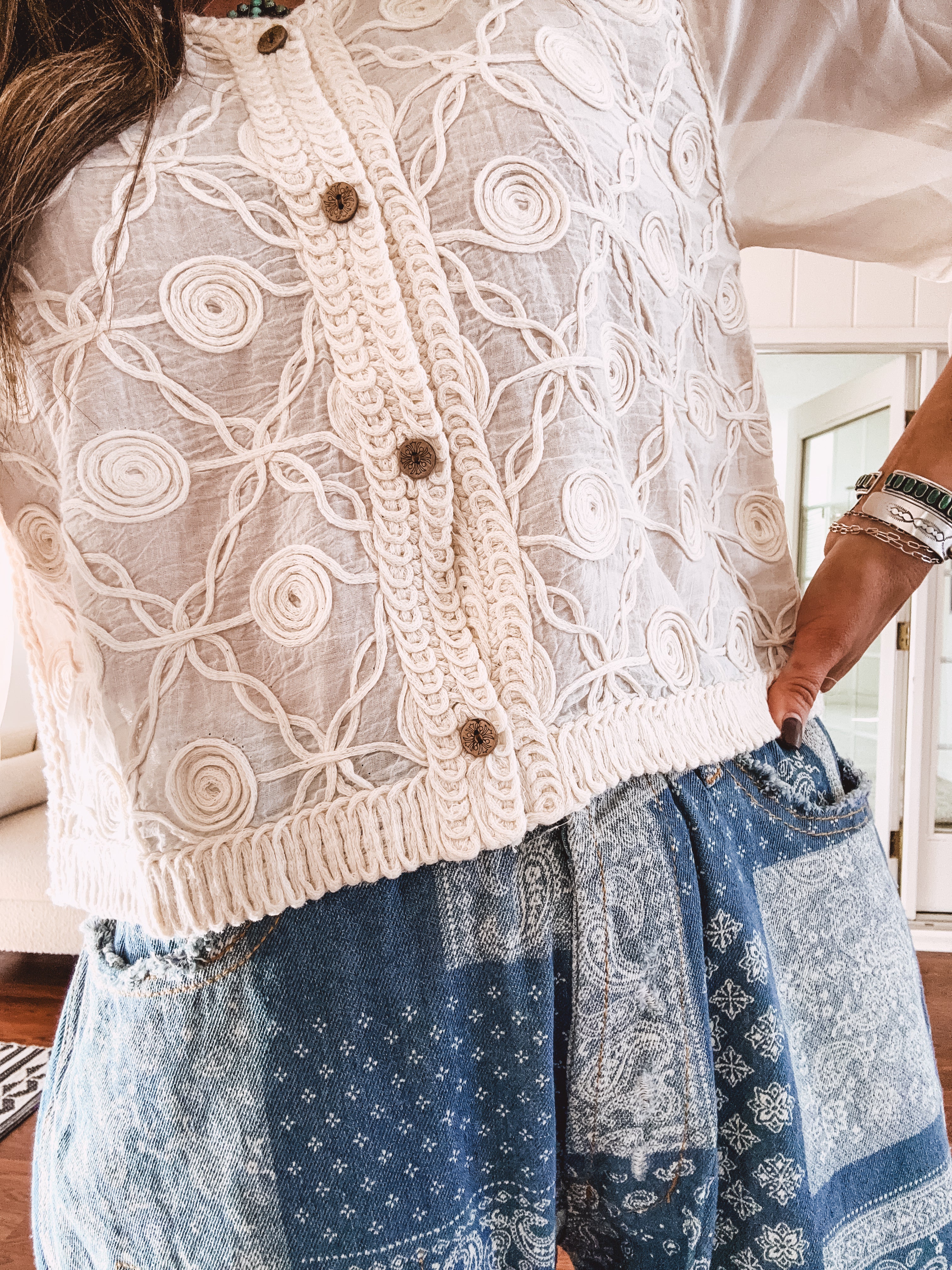 Short sheer beige button down long sleeved top with whimsical embroidery throughout and elastic cuffs.