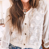 Short sheer beige button down long sleeved top with whimsical embroidery throughout and elastic cuffs.