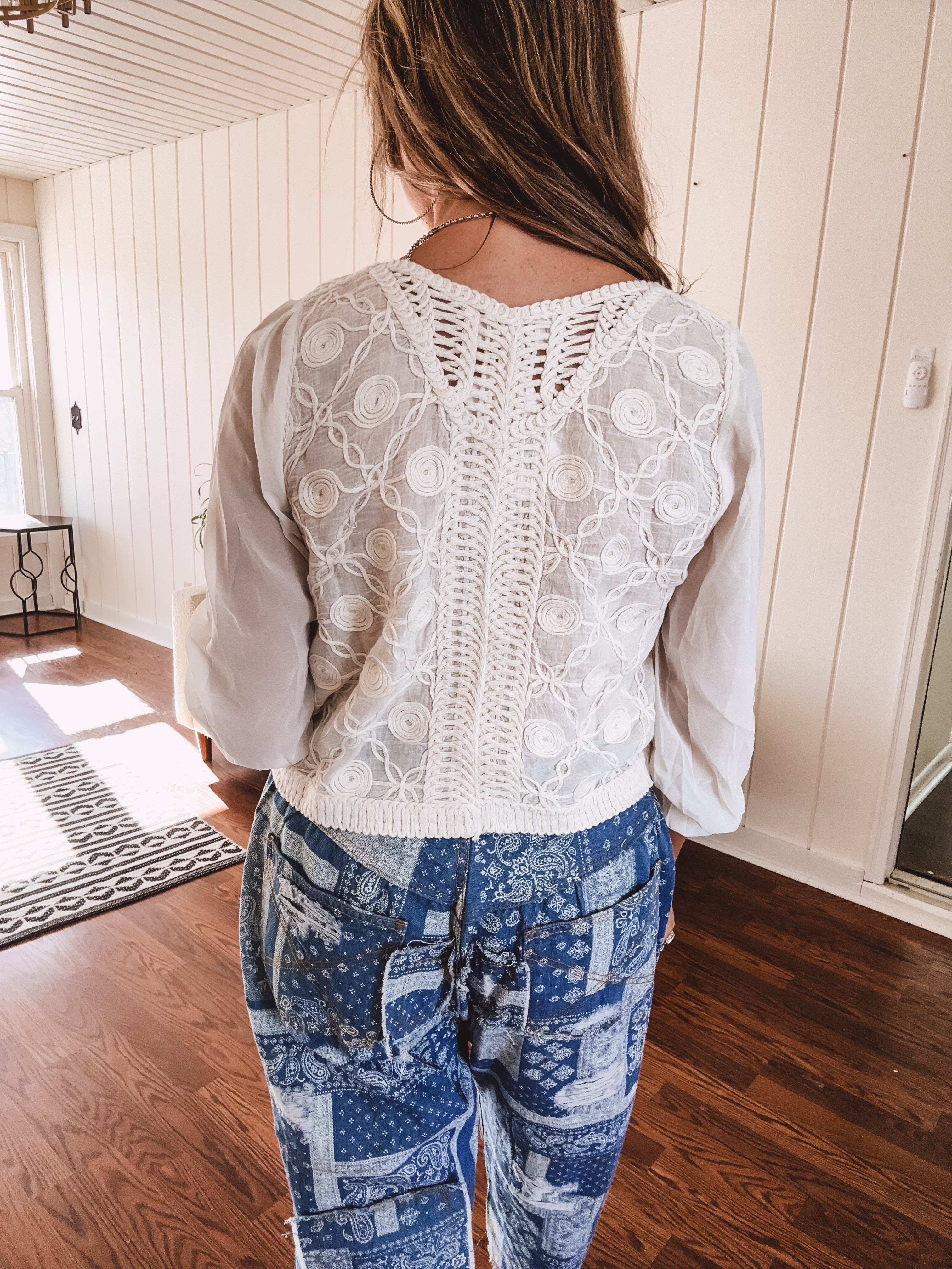 Short sheer beige button down long sleeved top with whimsical embroidery throughout and elastic cuffs.