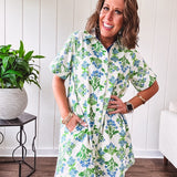 Cream shirt dress with blue and green floral print throughout, contrasting blue trim at the covered placket and hem, cuffed sleeves, mini length, fully lined.
