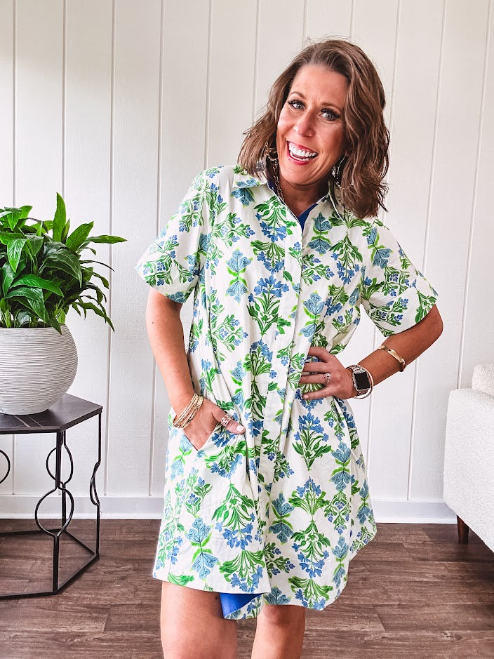 Cream shirt dress with blue and green floral print throughout, contrasting blue trim at the covered placket and hem, cuffed sleeves, mini length, fully lined.