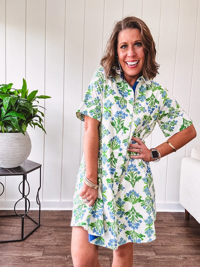 Cream shirt dress with blue and green floral print throughout, contrasting blue trim at the covered placket and hem, cuffed sleeves, mini length, fully lined.