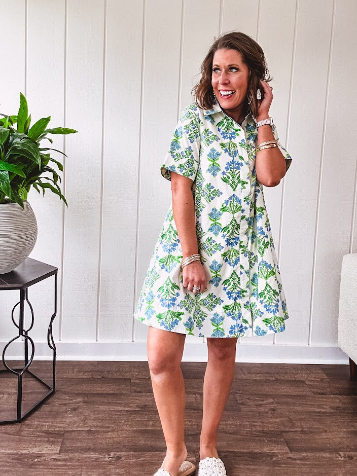 Cream shirt dress with blue and green floral print throughout, contrasting blue trim at the covered placket and hem, cuffed sleeves, mini length, fully lined.