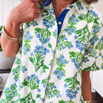 Cream shirt dress with blue and green floral print throughout, contrasting blue trim at the covered placket and hem, cuffed sleeves, mini length, fully lined.