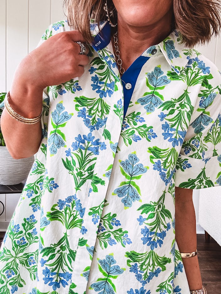 Cream shirt dress with blue and green floral print throughout, contrasting blue trim at the covered placket and hem, cuffed sleeves, mini length, fully lined.