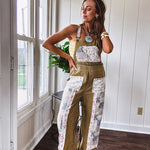 Light olive green washed cotton overalls with pastel floral patchwork throughout including on the adjustable traps with metal clasps and zippered sides.