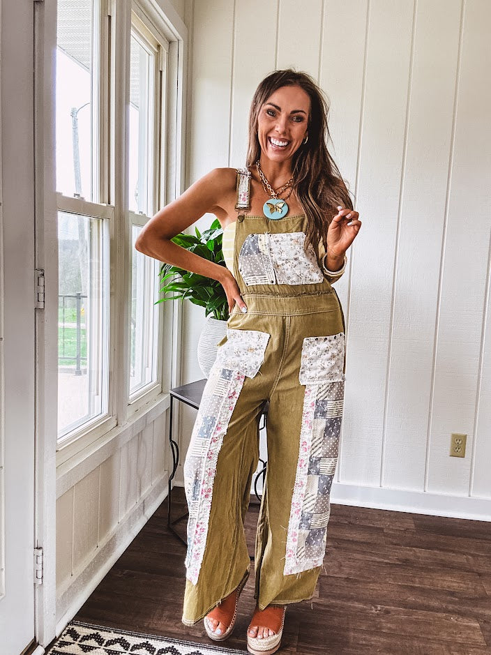Light olive green washed cotton overalls with pastel floral patchwork throughout including on the adjustable traps with metal clasps and zippered sides.