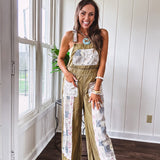 Light olive green washed cotton overalls with pastel floral patchwork throughout including on the adjustable traps with metal clasps and zippered sides.