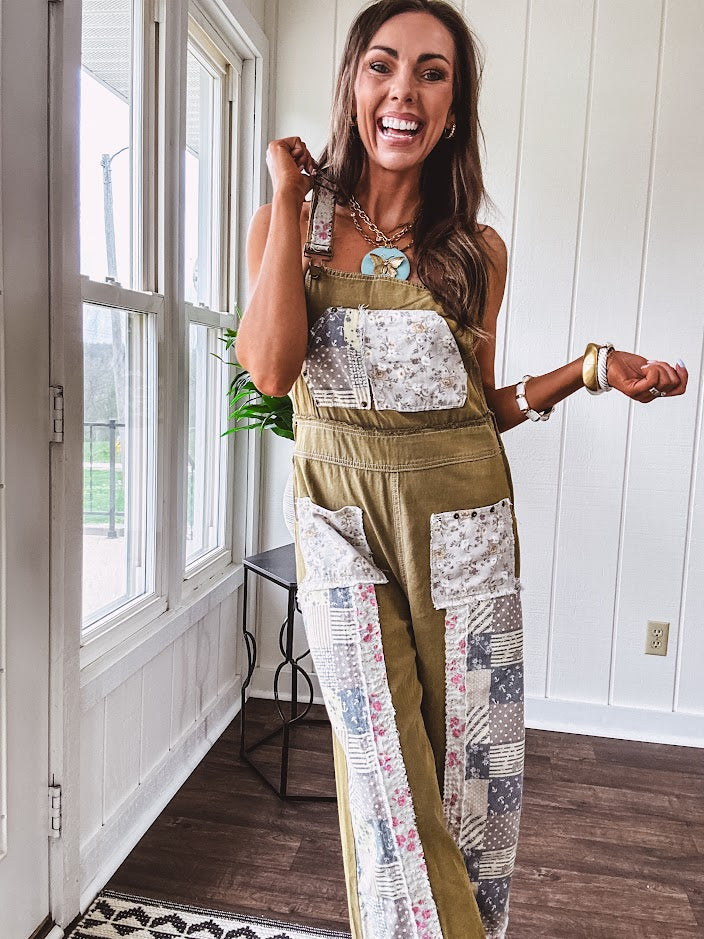 Light olive green washed cotton overalls with pastel floral patchwork throughout including on the adjustable traps with metal clasps and zippered sides.