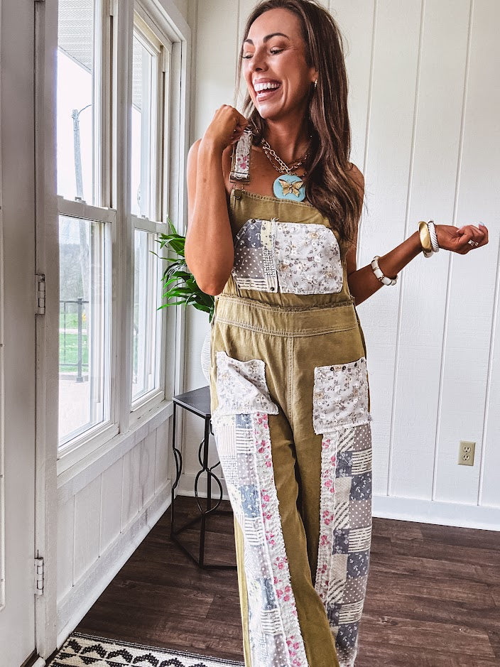 Light olive green washed cotton overalls with pastel floral patchwork throughout including on the adjustable traps with metal clasps and zippered sides.