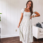 White dress with green dainty vines print, capped elastic sleeves and elastic square neckline, smocked bodice and tiered, fully lined skirt.