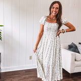 White dress with green dainty vines print, capped elastic sleeves and elastic square neckline, smocked bodice and tiered, fully lined skirt.
