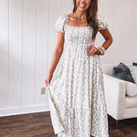 White dress with green dainty vines print, capped elastic sleeves and elastic square neckline, smocked bodice and tiered, fully lined skirt.