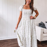 White dress with green dainty vines print, capped elastic sleeves and elastic square neckline, smocked bodice and tiered, fully lined skirt.