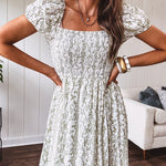 White dress with green dainty vines print, capped elastic sleeves and elastic square neckline, smocked bodice and tiered, fully lined skirt.