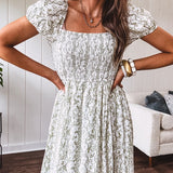 White dress with green dainty vines print, capped elastic sleeves and elastic square neckline, smocked bodice and tiered, fully lined skirt.