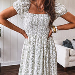 White dress with green dainty vines print, capped elastic sleeves and elastic square neckline, smocked bodice and tiered, fully lined skirt.