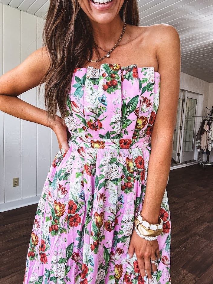 Pink strapless midi dress with floral and berry motif in red, blue and white with pleated front bodice and back smocked bodice, fully lined pleated skirt, with pockets.