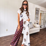 Soft, flowy wide leg pants with elastic waist, pockets and one leg featuring rust and black checks and the other cream with leo and black 8 ball motif.