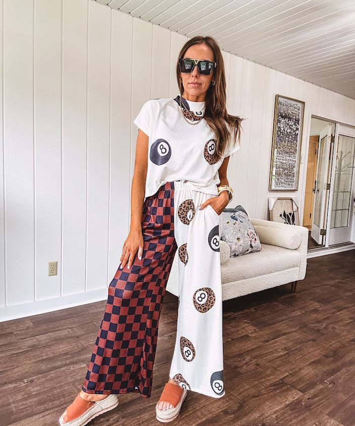 Soft cap sleeved mock neck cream top with a shorter waist and black and leo 8 ball motif throughout.