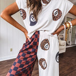 Soft, flowy wide leg pants with elastic waist, pockets and one leg featuring rust and black checks and the other cream with leo and black 8 ball motif.