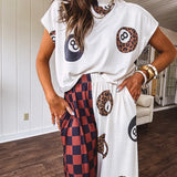 Soft, flowy wide leg pants with elastic waist, pockets and one leg featuring rust and black checks and the other cream with leo and black 8 ball motif.