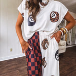 Soft cap sleeved mock neck cream top with a shorter waist and black and leo 8 ball motif throughout.