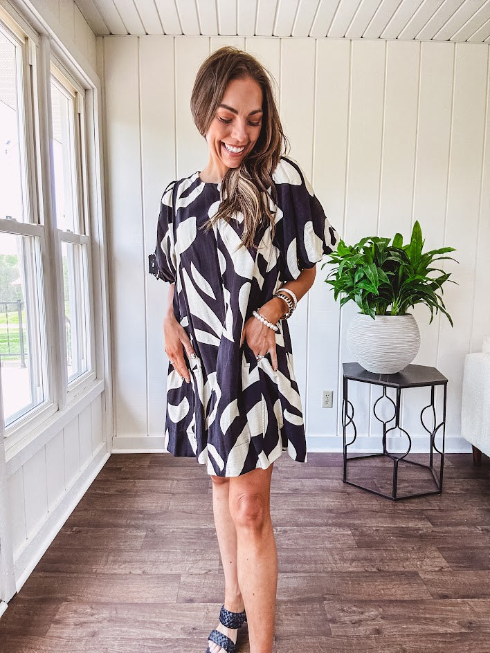 Short black and ivory abstract print dress, fully lined with hook and eye neck closure and puffed sleeves.