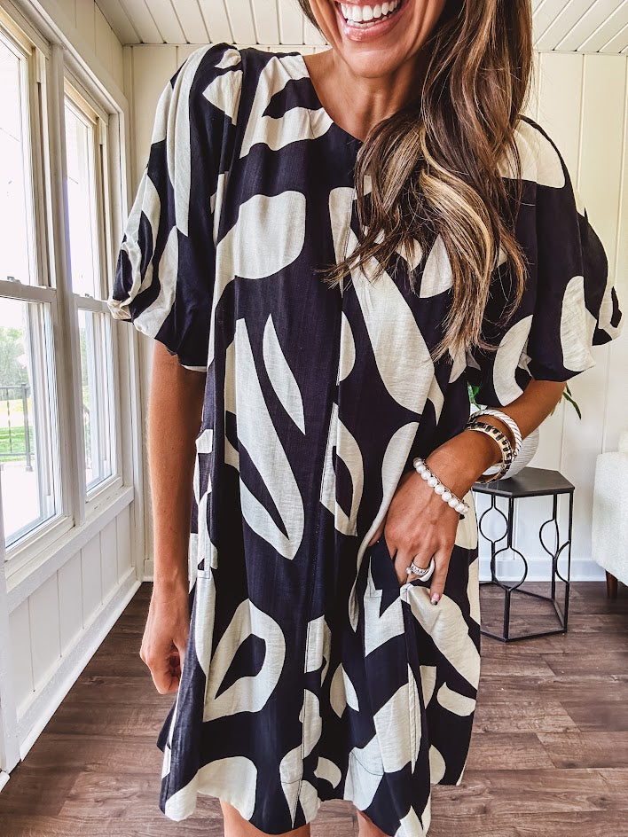 Short black and ivory abstract print dress, fully lined with hook and eye neck closure and puffed sleeves.