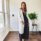Midi length ivory and small black polka dot long sleeved duster with silver buttons and pockets.