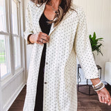 Midi length ivory and small black polka dot long sleeved duster with silver buttons and pockets.