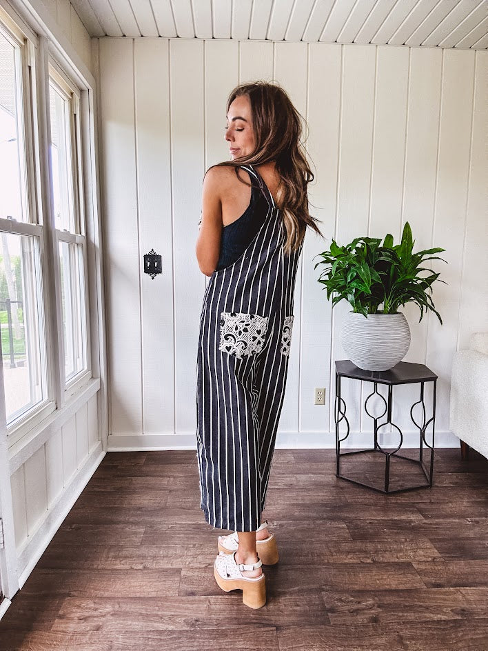 Thin, lightweight black and ivory striped overalls featuring black and ivory lace crochet patches throughout and faux wooden buttons at the adjustable straps and sides.