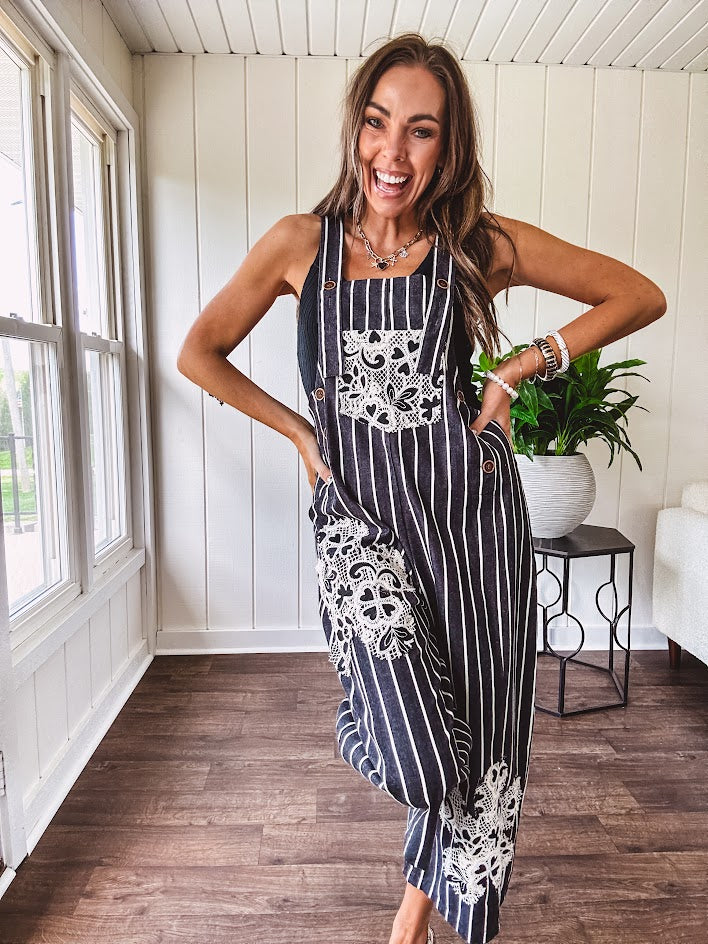 Thin, lightweight black and ivory striped overalls featuring black and ivory lace crochet patches throughout and faux wooden buttons at the adjustable straps and sides.