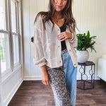 Oatmeal crochet short cardigan with long sleeves and floral motif with three faux wooden button closure.