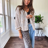 Oatmeal crochet short cardigan with long sleeves and floral motif with three faux wooden button closure.