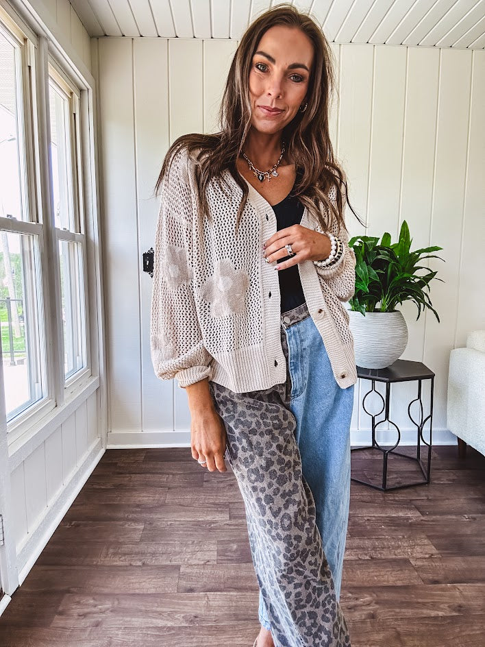 Oatmeal crochet short cardigan with long sleeves and floral motif with three faux wooden button closure.