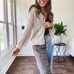 Oatmeal crochet short cardigan with long sleeves and floral motif with three faux wooden button closure.