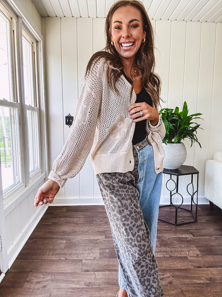 Oatmeal crochet short cardigan with long sleeves and floral motif with three faux wooden button closure.
