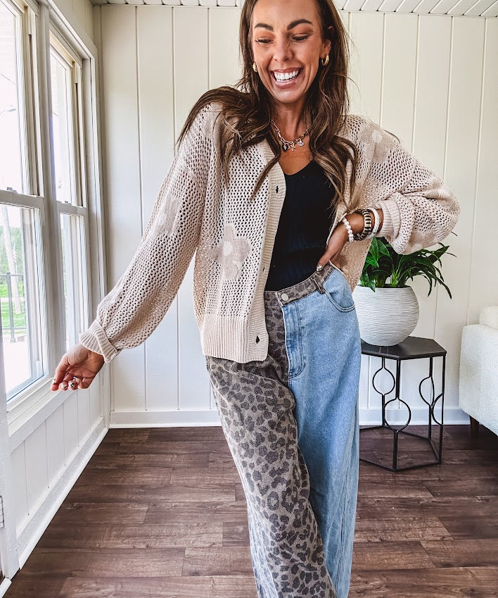 Oatmeal crochet short cardigan with long sleeves and floral motif with three faux wooden button closure.