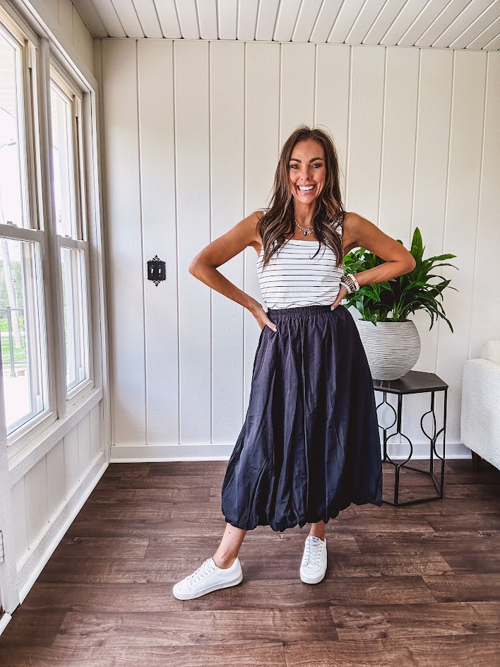 Midi length black athletic style bubble hem skirt with elastic waist and pockets.