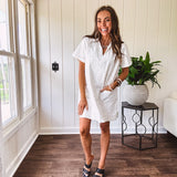 Lined cream denim-like short shift dress with V neck and collar, short sleeves,, contrasting tan stitching, front pocket and eyelet details throughout