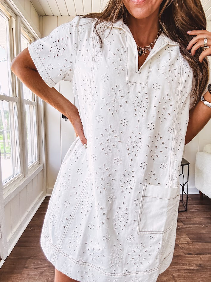 Lined cream denim-like short shift dress with V neck and collar, short sleeves,, contrasting tan stitching, front pocket and eyelet details throughout