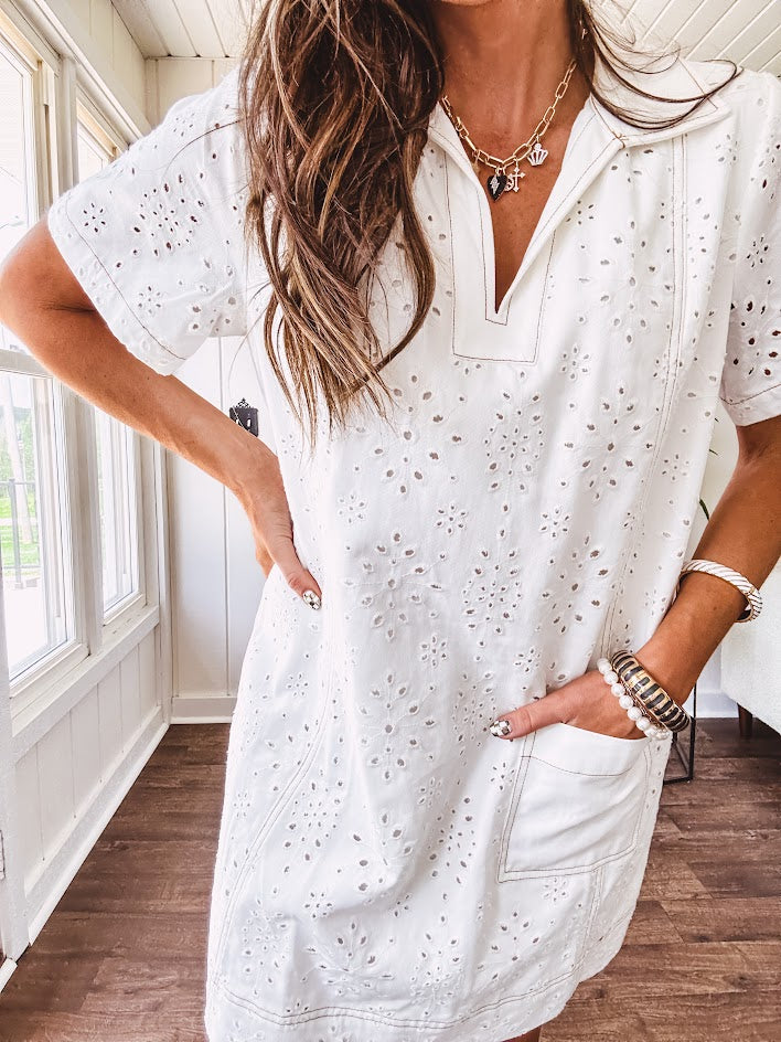 Lined cream denim-like short shift dress with V neck and collar, short sleeves,, contrasting tan stitching, front pocket and eyelet details throughout