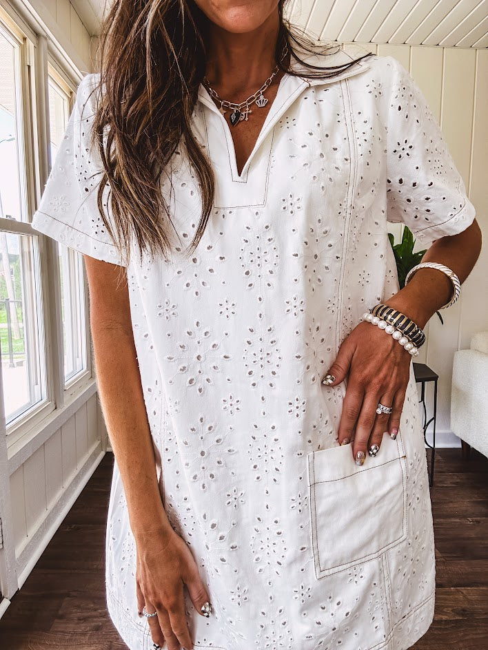 Lined cream denim-like short shift dress with V neck and collar, short sleeves,, contrasting tan stitching, front pocket and eyelet details throughout