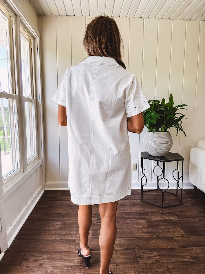 Lined cream denim-like short shift dress with V neck and collar, short sleeves,, contrasting tan stitching, front pocket and eyelet details throughout
