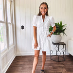 Fully lined white button down front dress with mock neck, V neck, short puffed sleeves, front pocket and elastic bands at the waist for a cinched waist look.